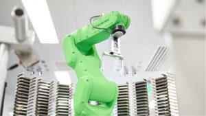 A green robot arm waiting for the next set of plates to be delivered to it
