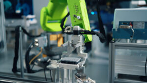 An automated workflow featuring a green robotic arm manipulating a set of samples in a plate that are on a maglev cart