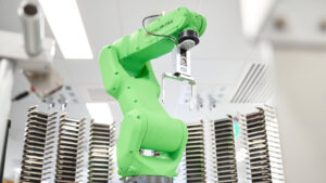 A green robot arm waiting for the next set of plates to be delivered to it